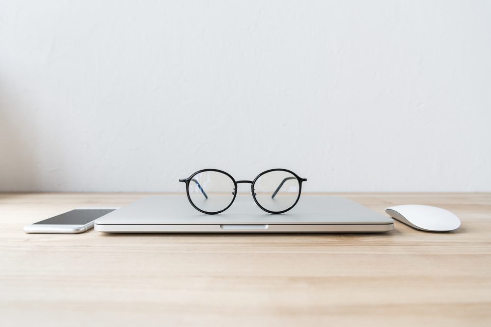 folded laptop at workplace with eyeglasses, smartphone and mouse