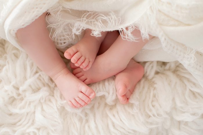 A closeup shot of the feet of twin girl babies. Shot in the studio on a sheepskin rug.