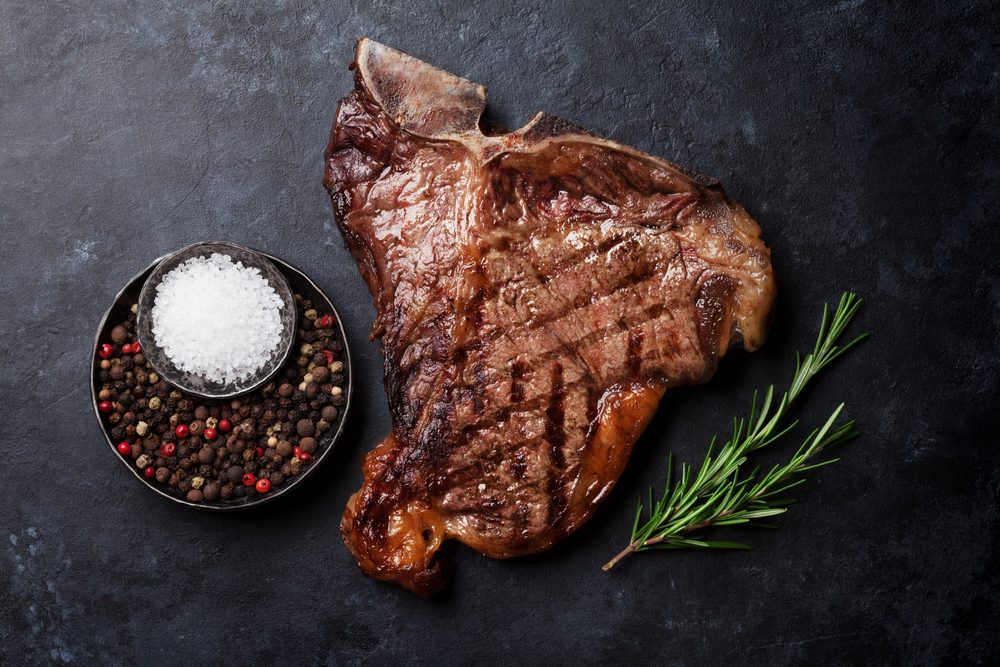Grilled T-bone steak on stone table. Top view