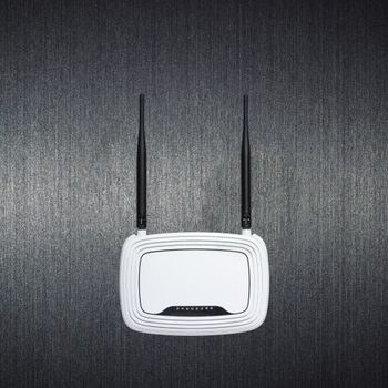 Router with antennas mounted on textured dark wall, idle.