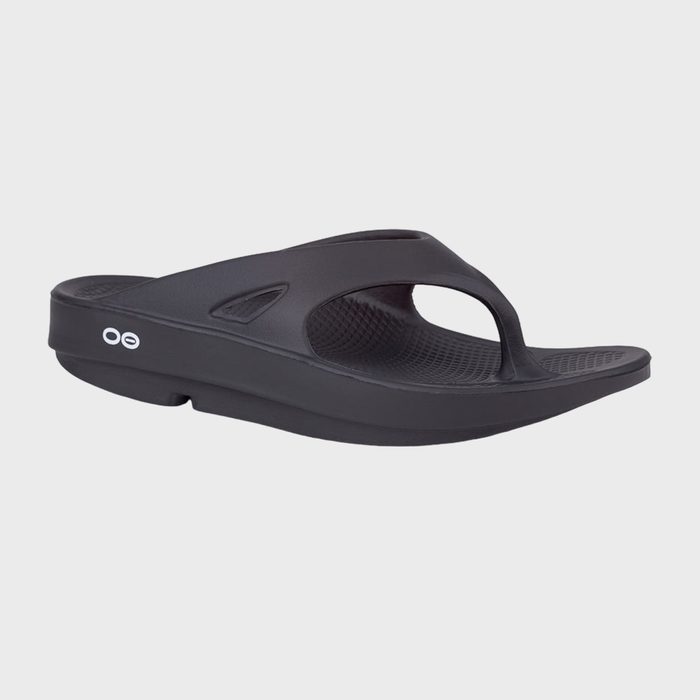 A black sandal rests, showing a thick sole and strap, against a plain white background.