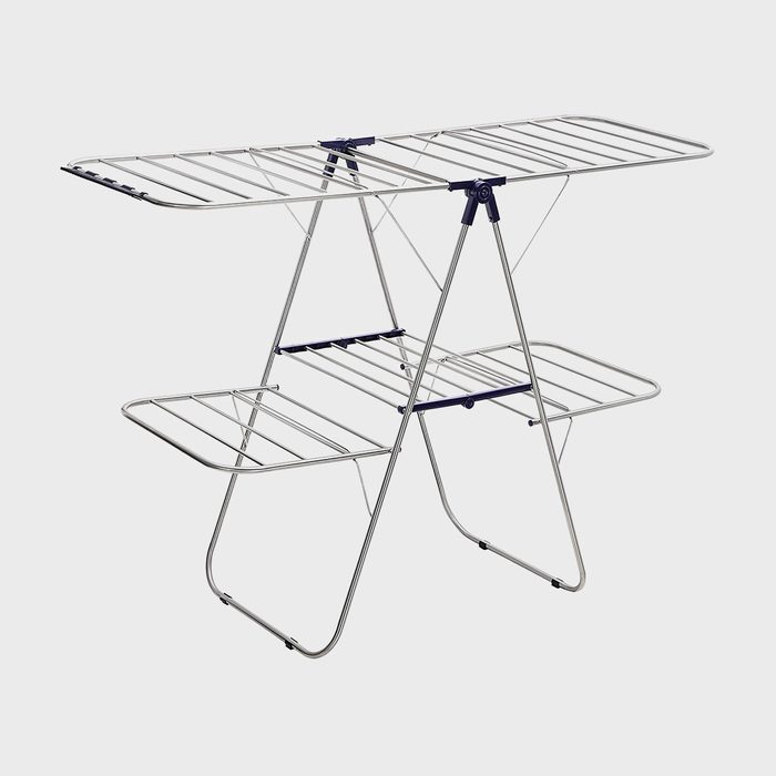 A metal drying rack stands open with three tiers, positioned against a plain, light gray background.