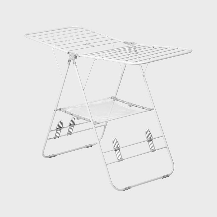 A white folding clothes drying rack stands open on a plain gray background.