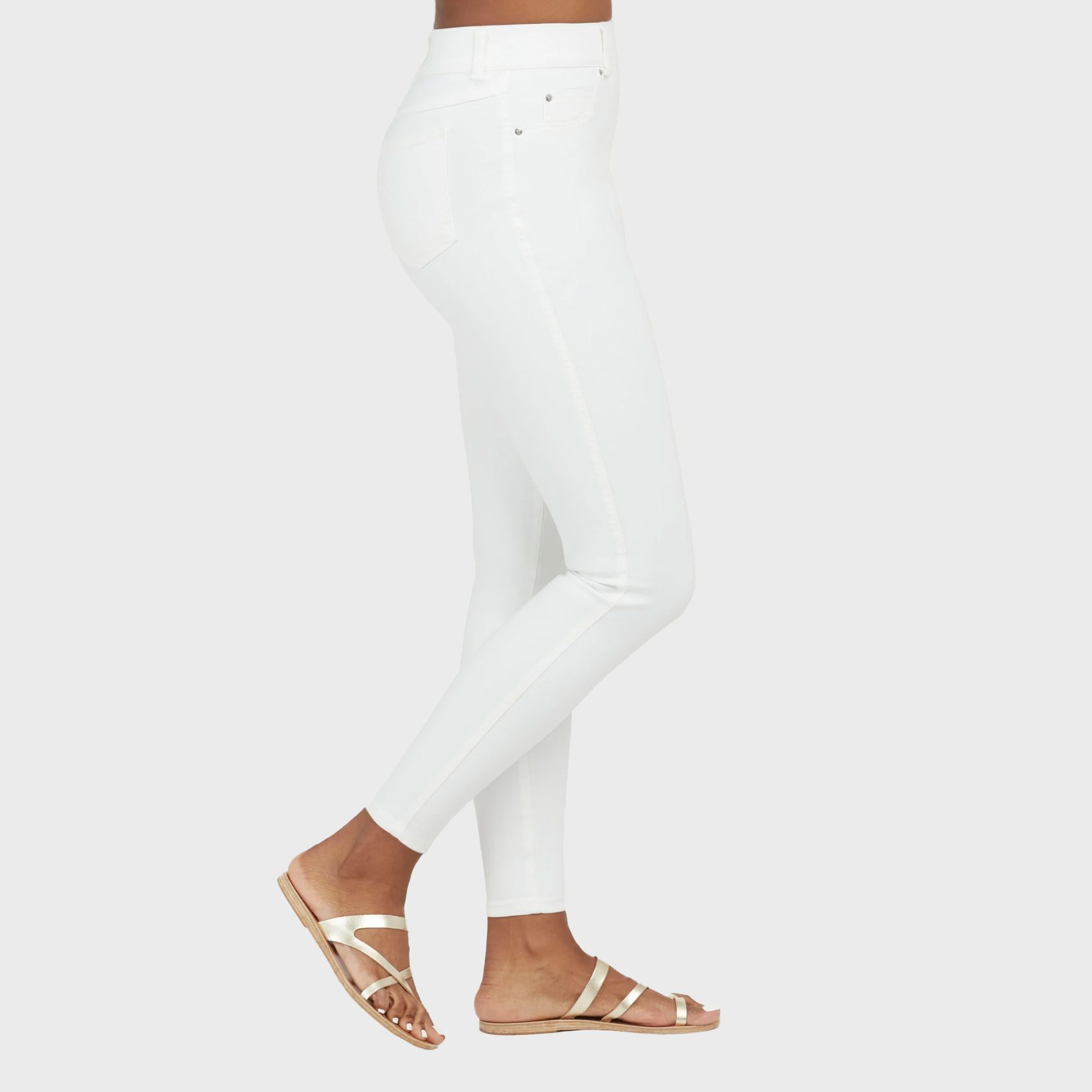 White leggings worn, paired with metallic sandals; standing against a plain white background.