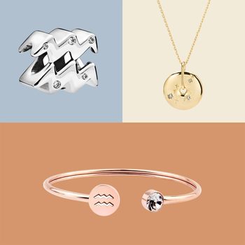 A silver ring, golden necklace, and rose-gold bracelet featuring zodiac symbols rest on pastel backgrounds.