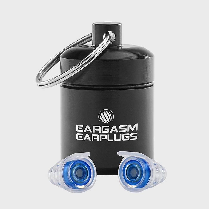 Earplugs rest in front of a black, cylindrical metal case with keyring, labeled â€œEargasm Earplugs,â€ on a plain background.