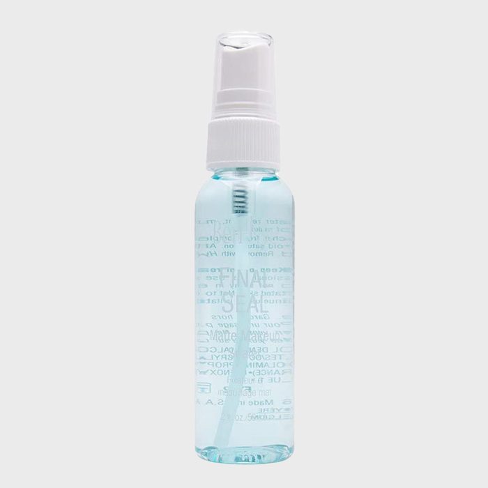 A transparent bottle containing blue liquid with a white spray nozzle, standing upright against a plain gray background.