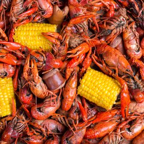 Red crawfish surround corn on the cob, creating a vibrant seafood boil scene.