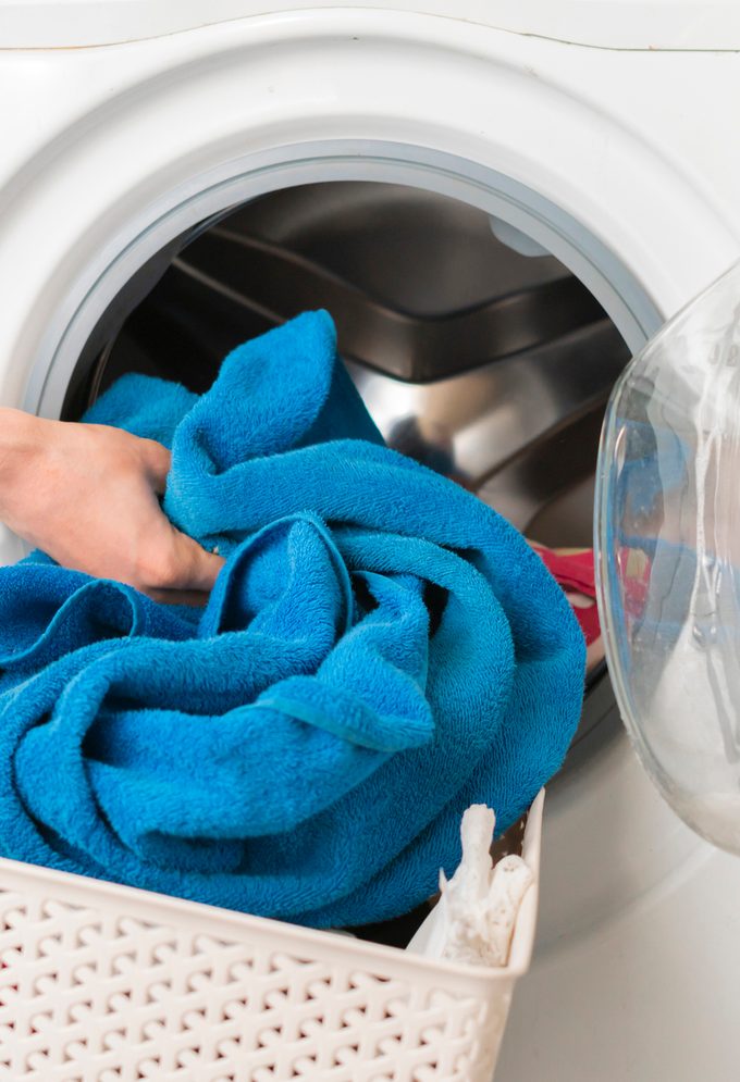 persons hand put dirty clothes in the washing machine b