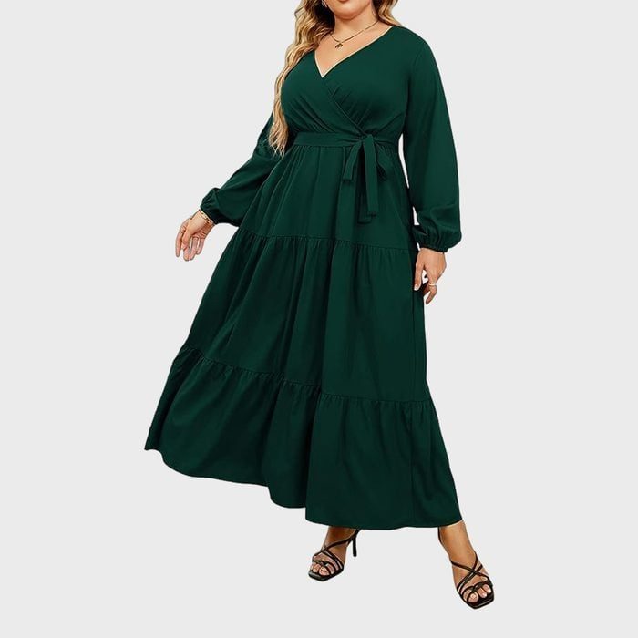 Woman wearing a long, flowing dark green dress with balloon sleeves, posed against a plain white background.