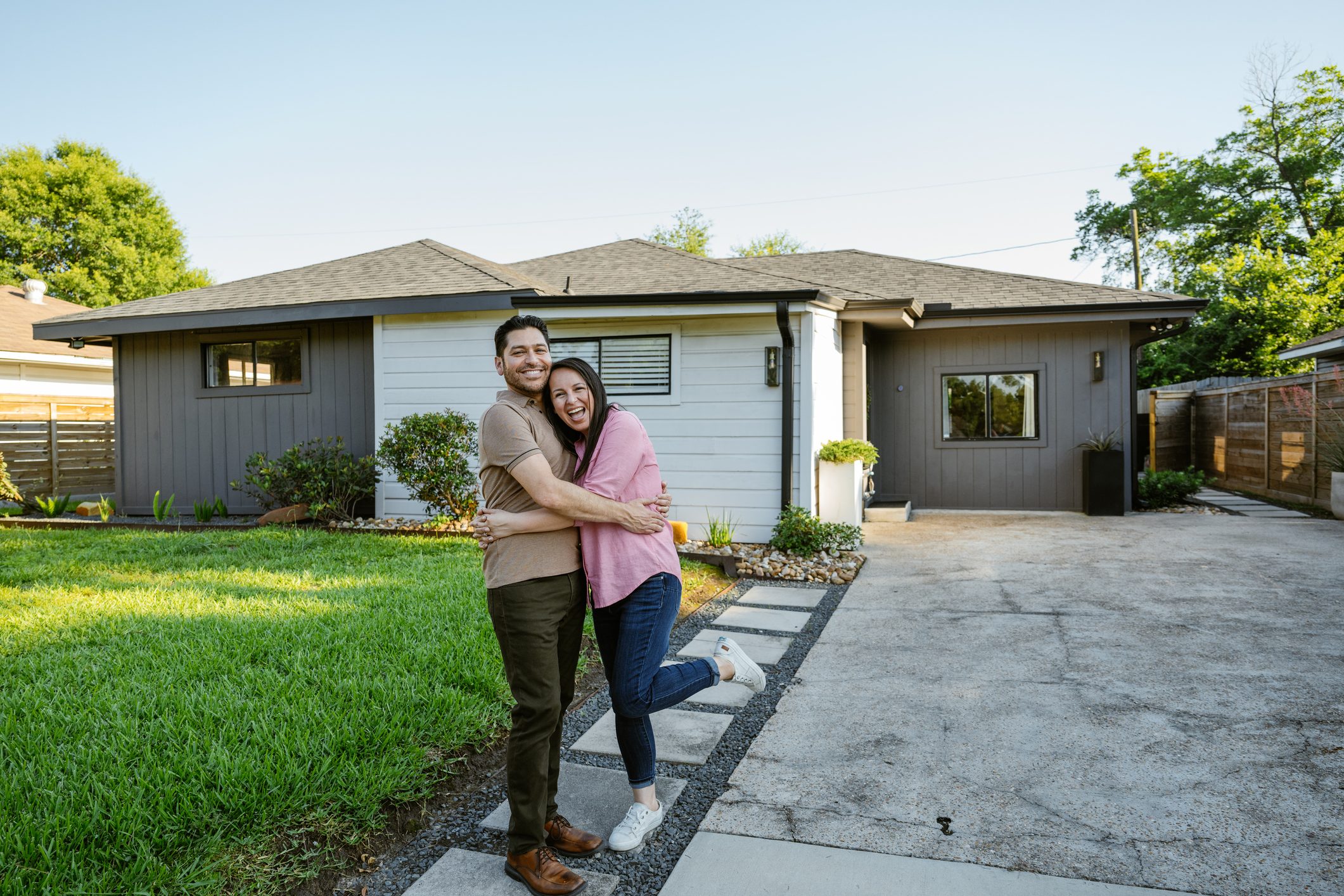 Mature couple proudly posing in front of newly bought house