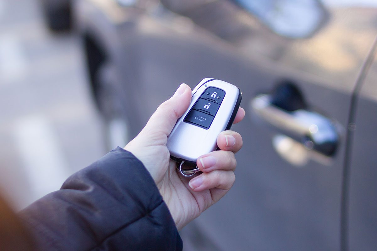 Woman holding car remote control, locking or unlocking vehicle