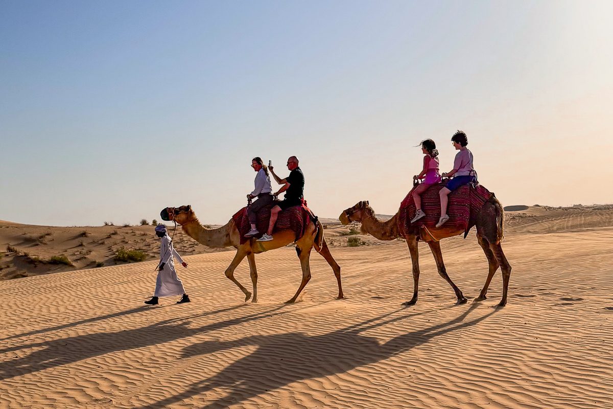 family riding camels in the desert